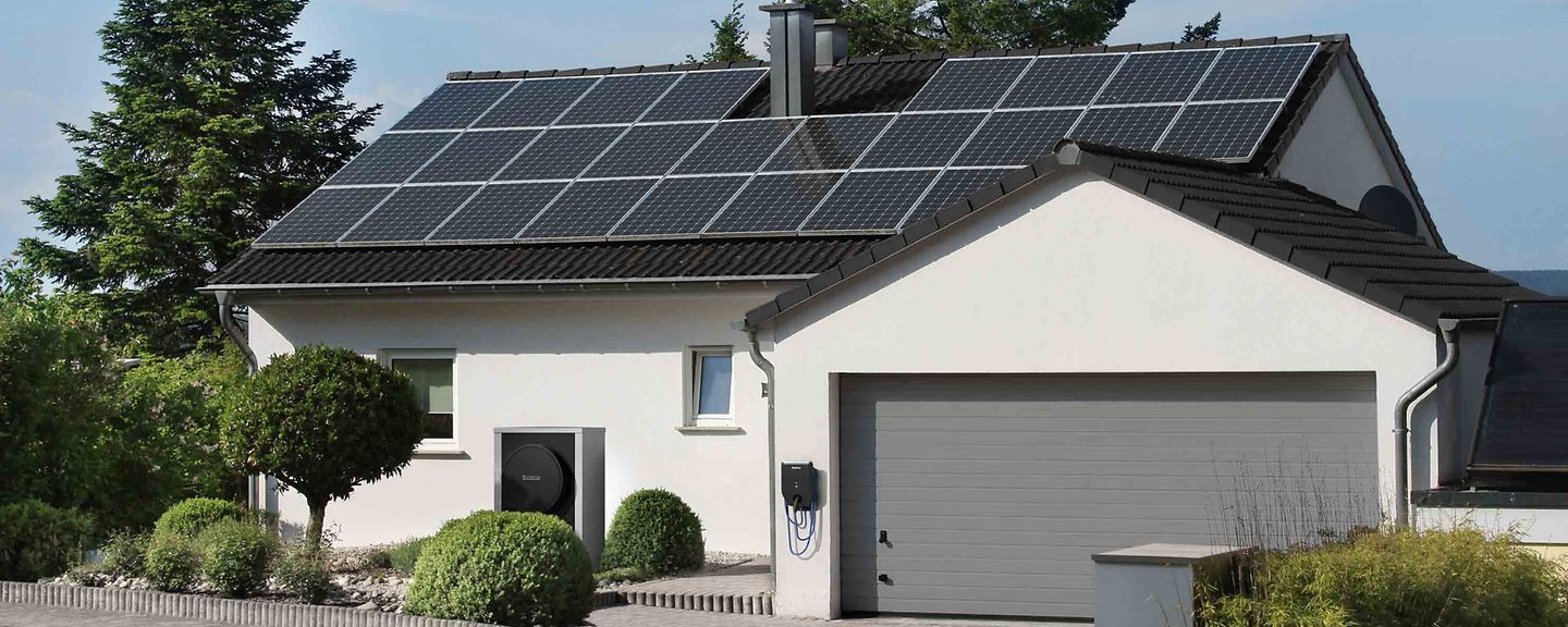 Ein weißes Haus mit einer Garage und Solarzellen auf dem Dach.